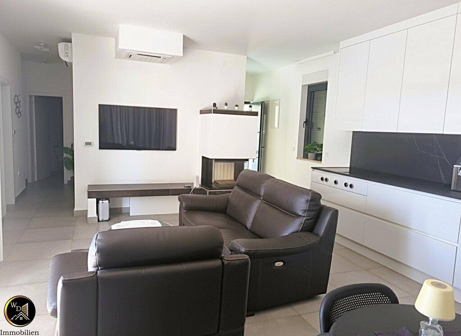 Offener Wohnbereich mit bequemen Sofas, Kamin und integrierter moderner Küche.