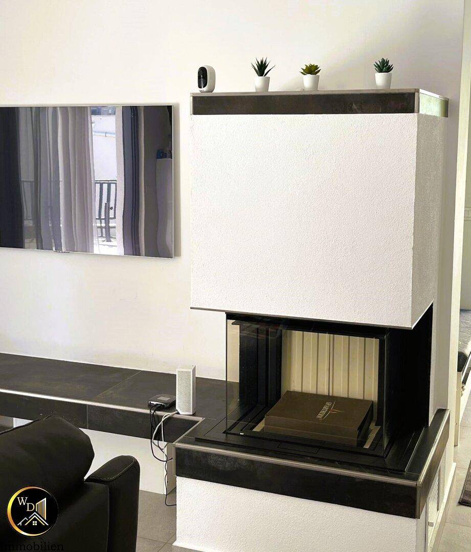 Moderner Kamin als zentrales Element im Wohnbereich, mit dekorativen Pflanzen.