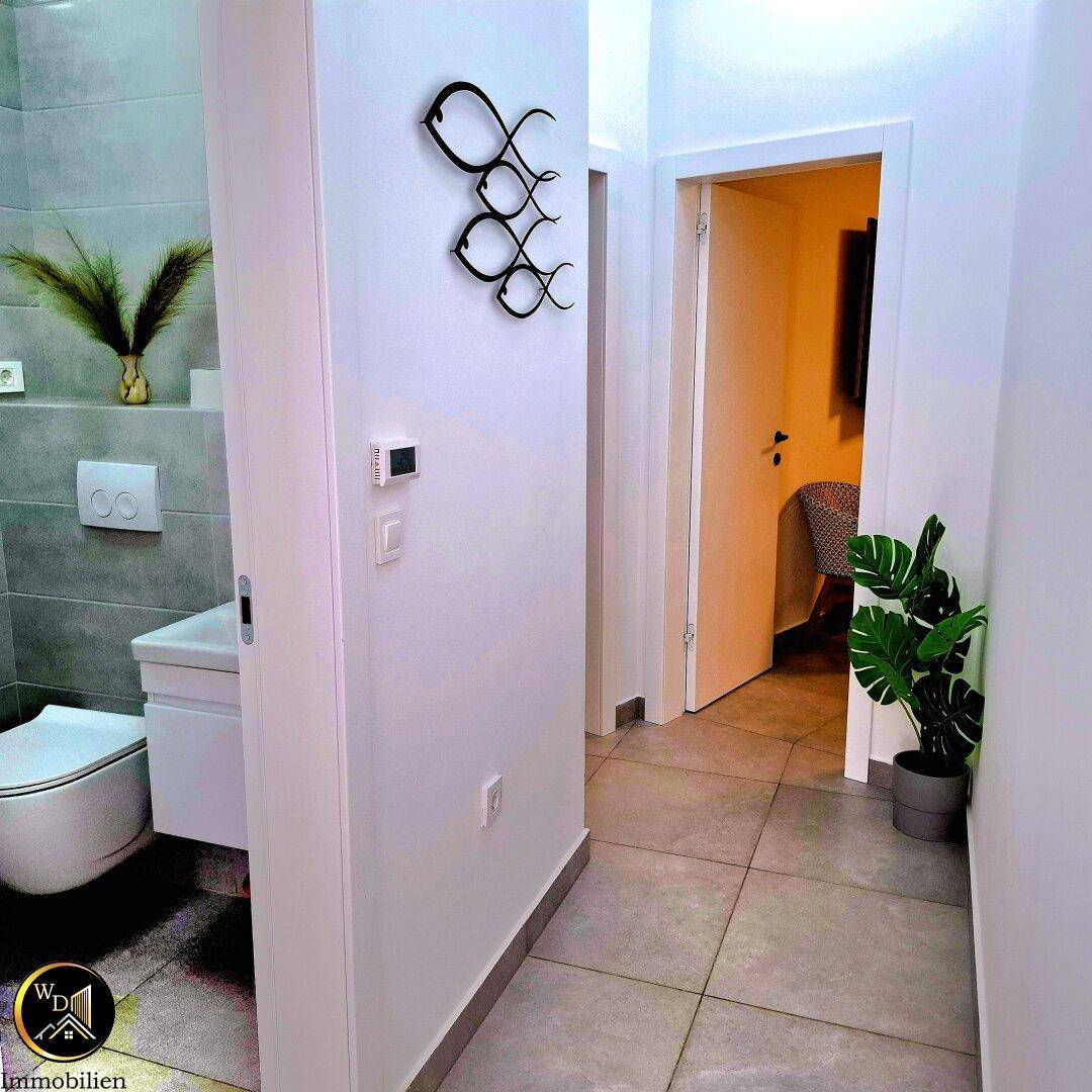 Heller Flur mit modernem Wand-WC und Fliesenboden, schlicht und funktional.