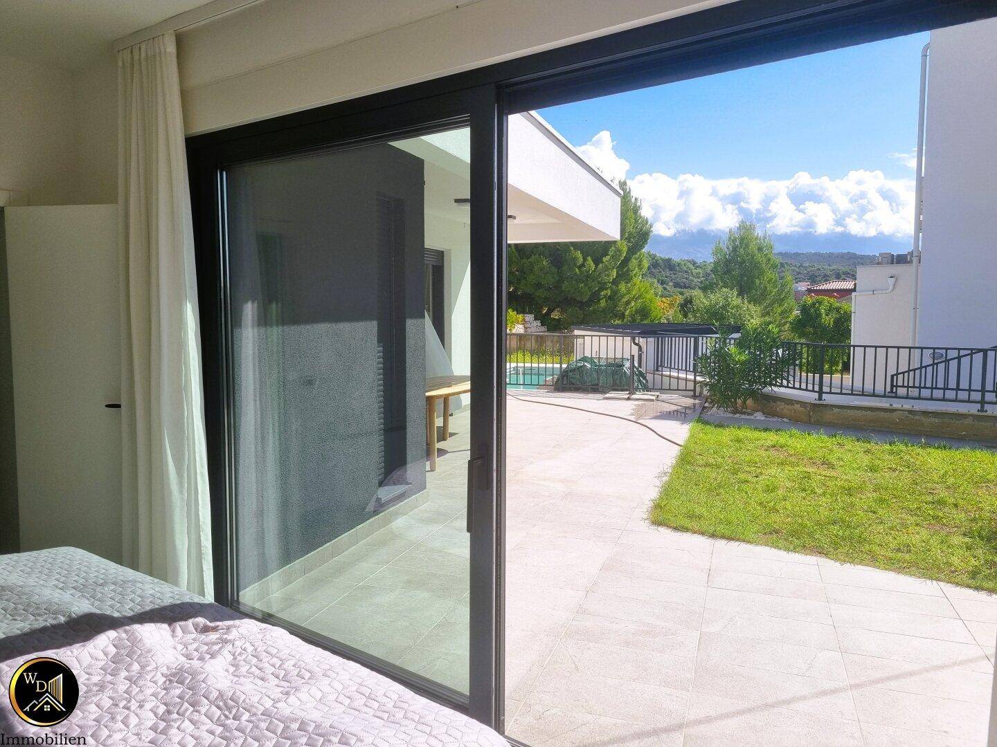 Helles Schlafzimmer mit großem Bett und Schiebetür, die Zugang zum Außenbereich bietet.
