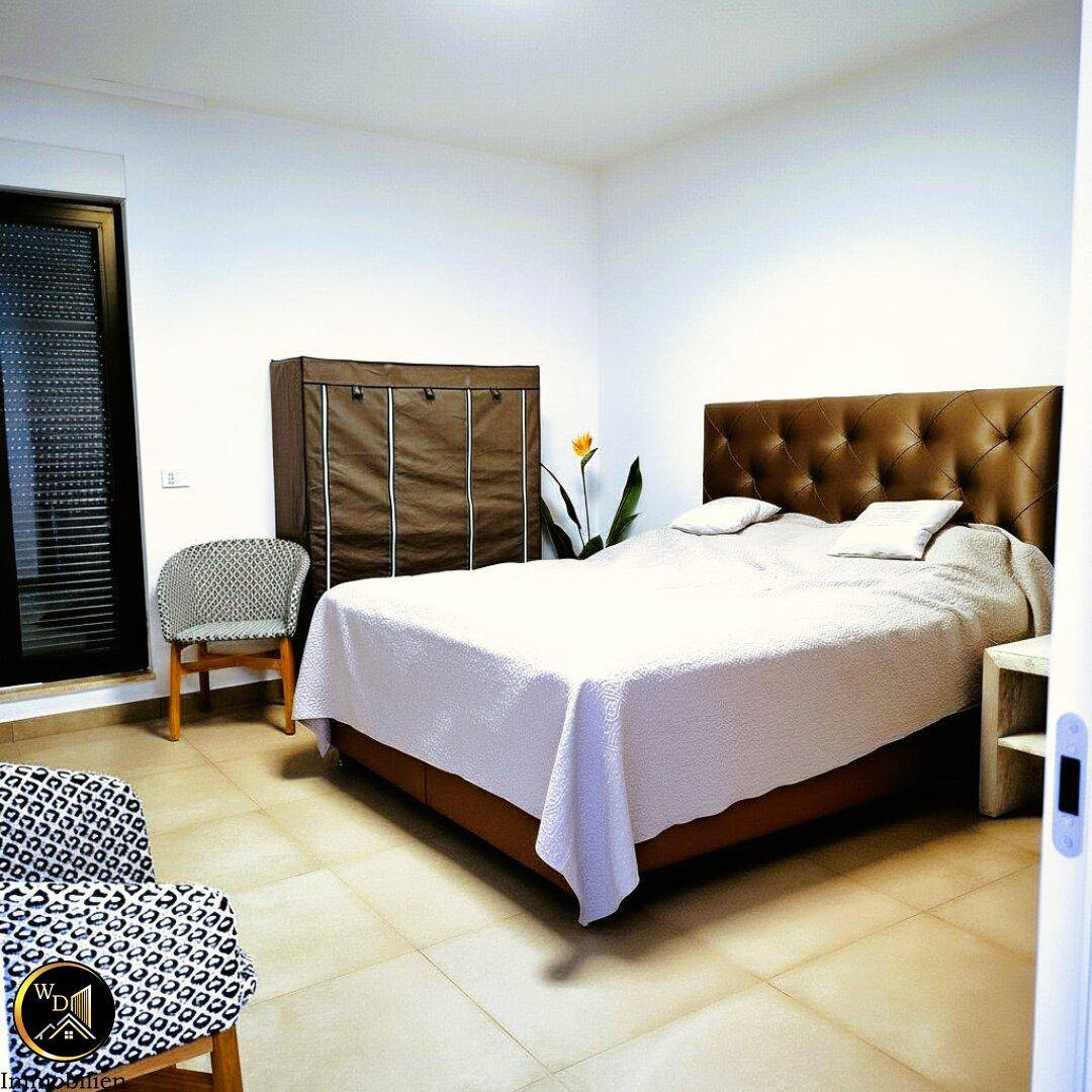 Schlafzimmer mit Doppelbett, mobilem Kleiderschrank und Fliesenboden.