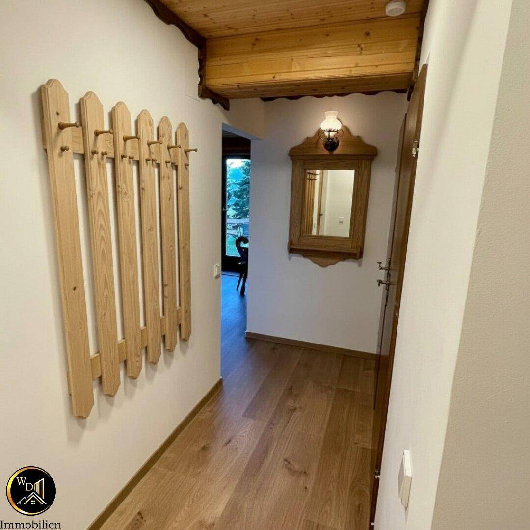 Heller Flur mit Holzpaneeldecke, Holzboden und rustikaler Garderobe sowie Spiegel.