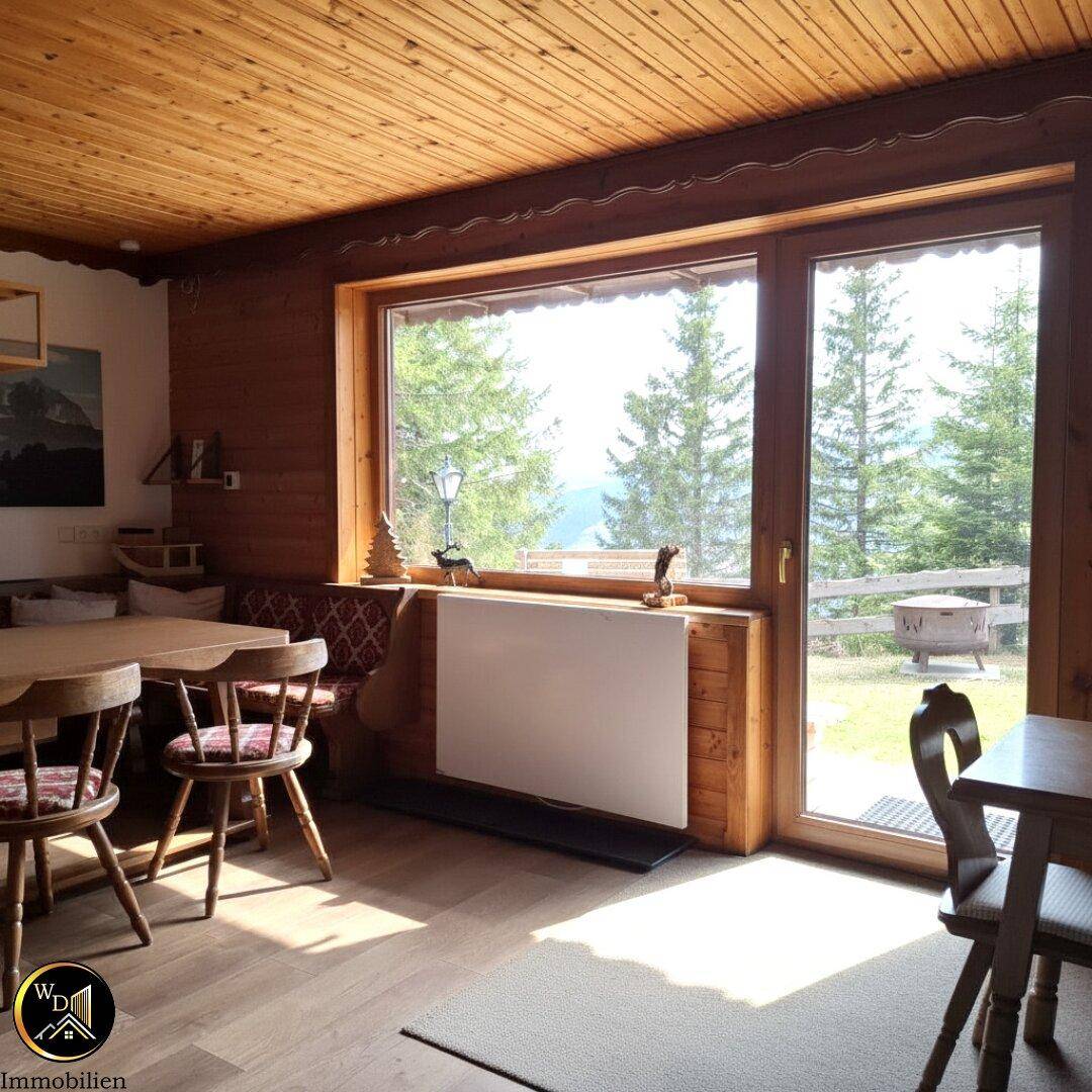 Heller Essbereich mit Holztisch und Zugang zum Garten, umgeben von Nadelbäumen.