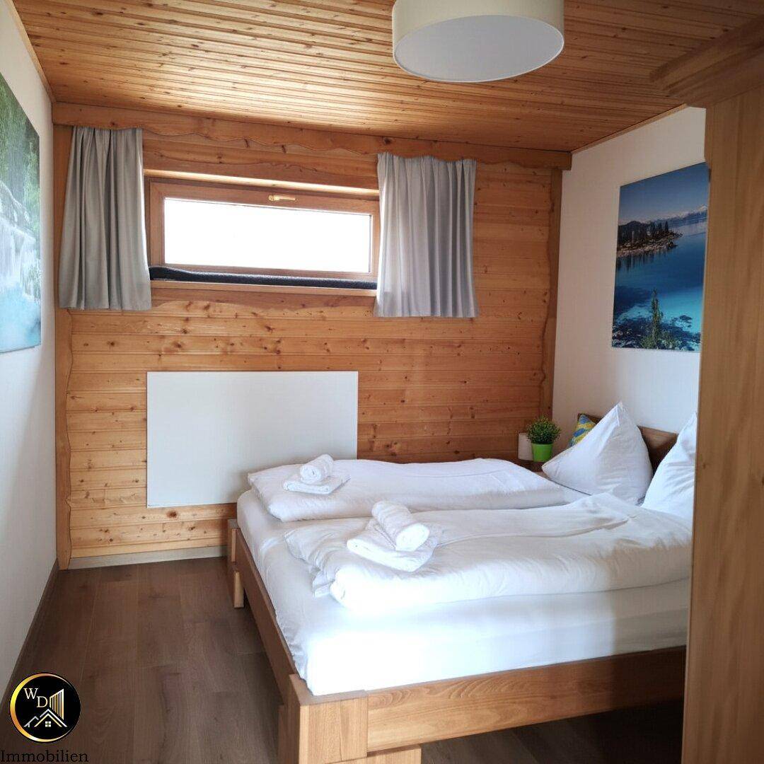 Schlafzimmer mit Doppelbett, Holzdecke und Holzwänden, sowie einem Fenster für Tageslicht.