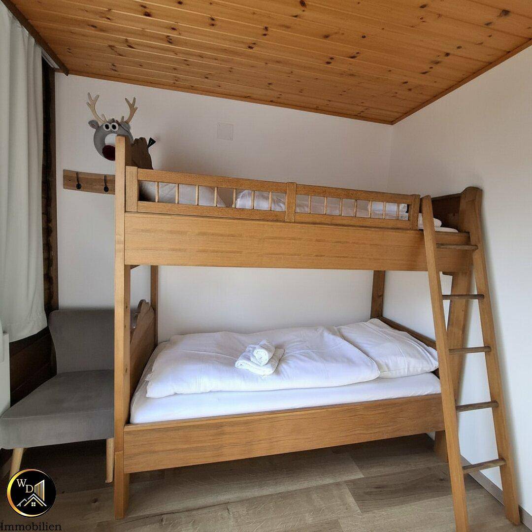 Gemütliches Schlafzimmer mit Etagenbett, Holzdecke und alpiner Dekoration.