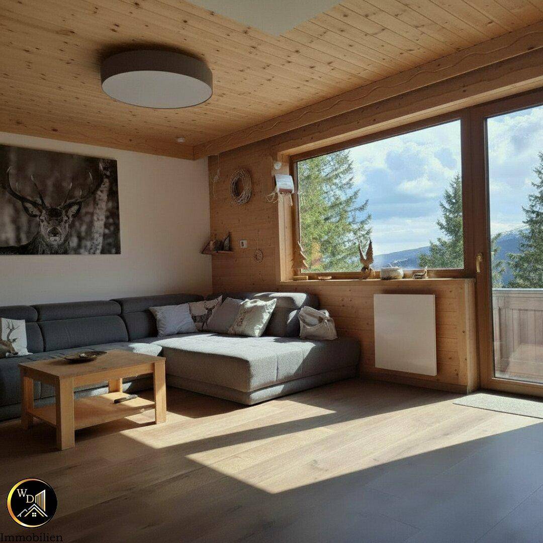 Helles Wohnzimmer mit großem Sofa, Holzwänden und weitem Bergblick durch die Fenster.