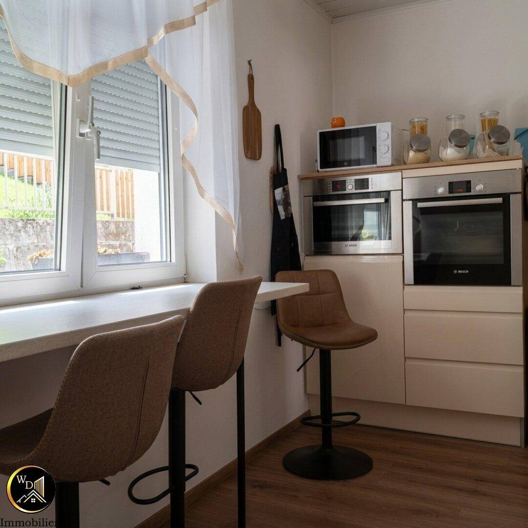 Moderne Küche mit Einbaugeräten, Frühstücksbar und Fenster mit Rollladen.