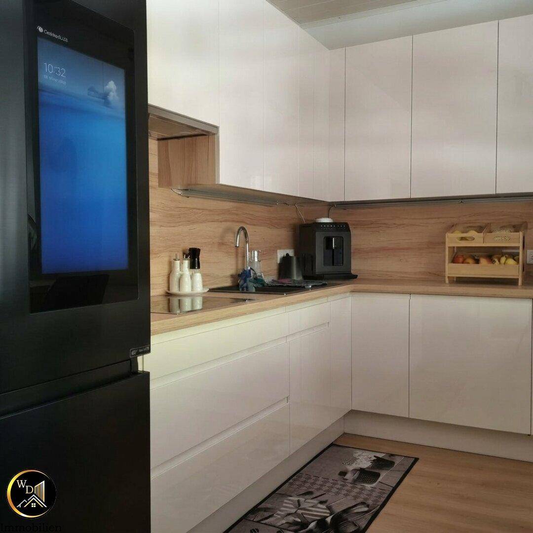 Moderne Einbauküche mit weißen Fronten, Holzakzenten und integriertem Kühlschrank.