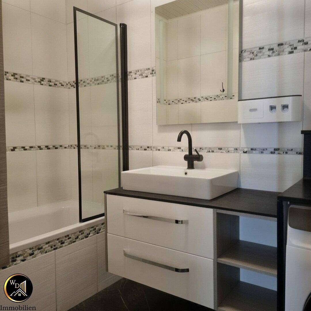 Modernes Badezimmer mit Badewanne, Duschwand und Waschtisch mit Unterschrank.