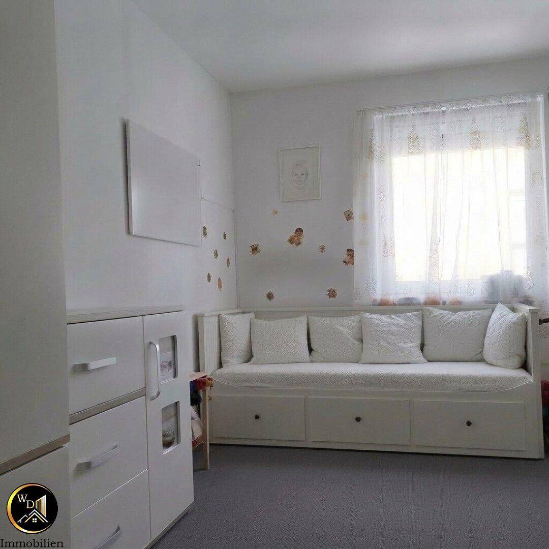 Kinderzimmer oder Gästezimmer mit Tagesbett, Teppichboden und hellem Fenster.