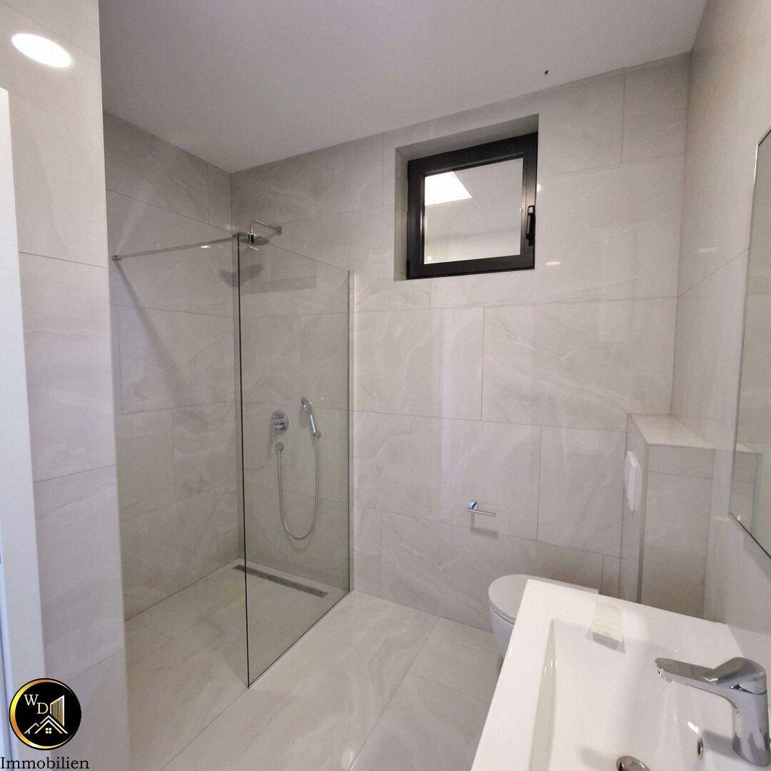 Modernes Badezimmer mit begehbarer Dusche, Wand-WC und Fenster.