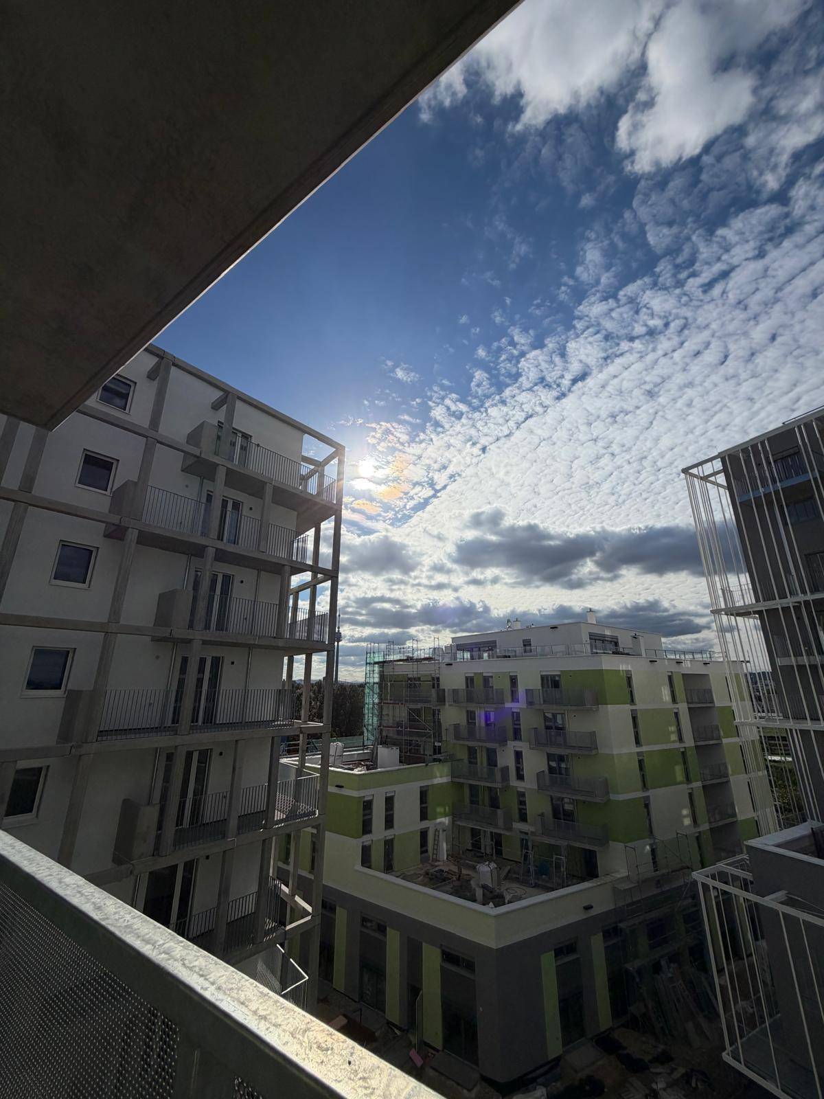 Panoramablick vom Balkon auf moderne Wohngebäude unter einem bewölkten Himmel, der die Umgebung zeigt.