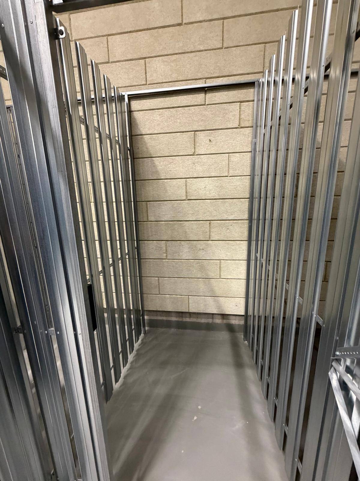 Abstellraum mit Metallabtrennungen und Betonboden, ideal für zusätzlichen Stauraum oder Fahrräder.