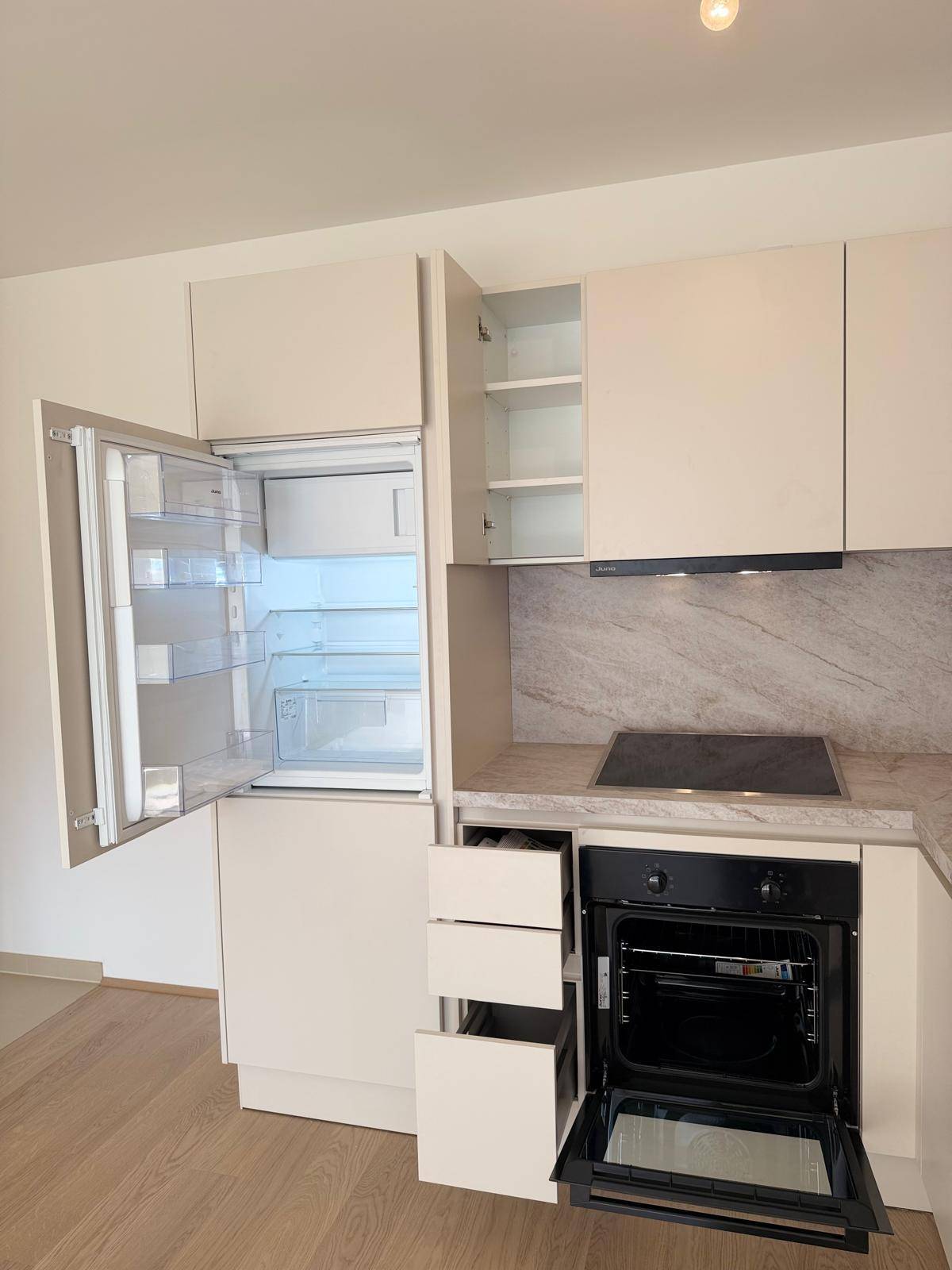 Detailansicht der Küche mit geöffnetem Kühlschrank, Backofen und Schubladen, die die Funktionalität zeigen.