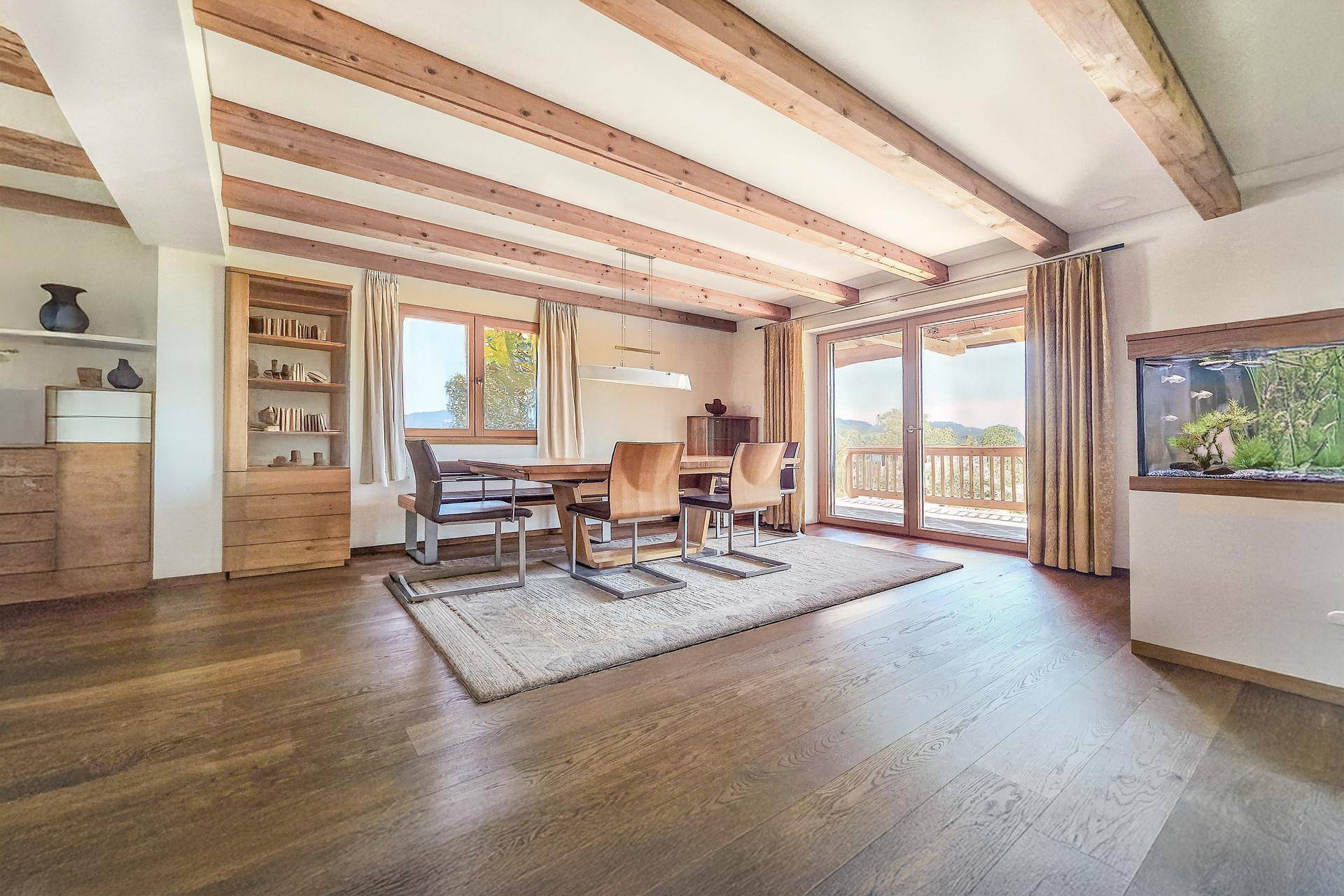 Heller Essbereich mit Holzbalkendecke, großem Esstisch und Zugang zur Terrasse.