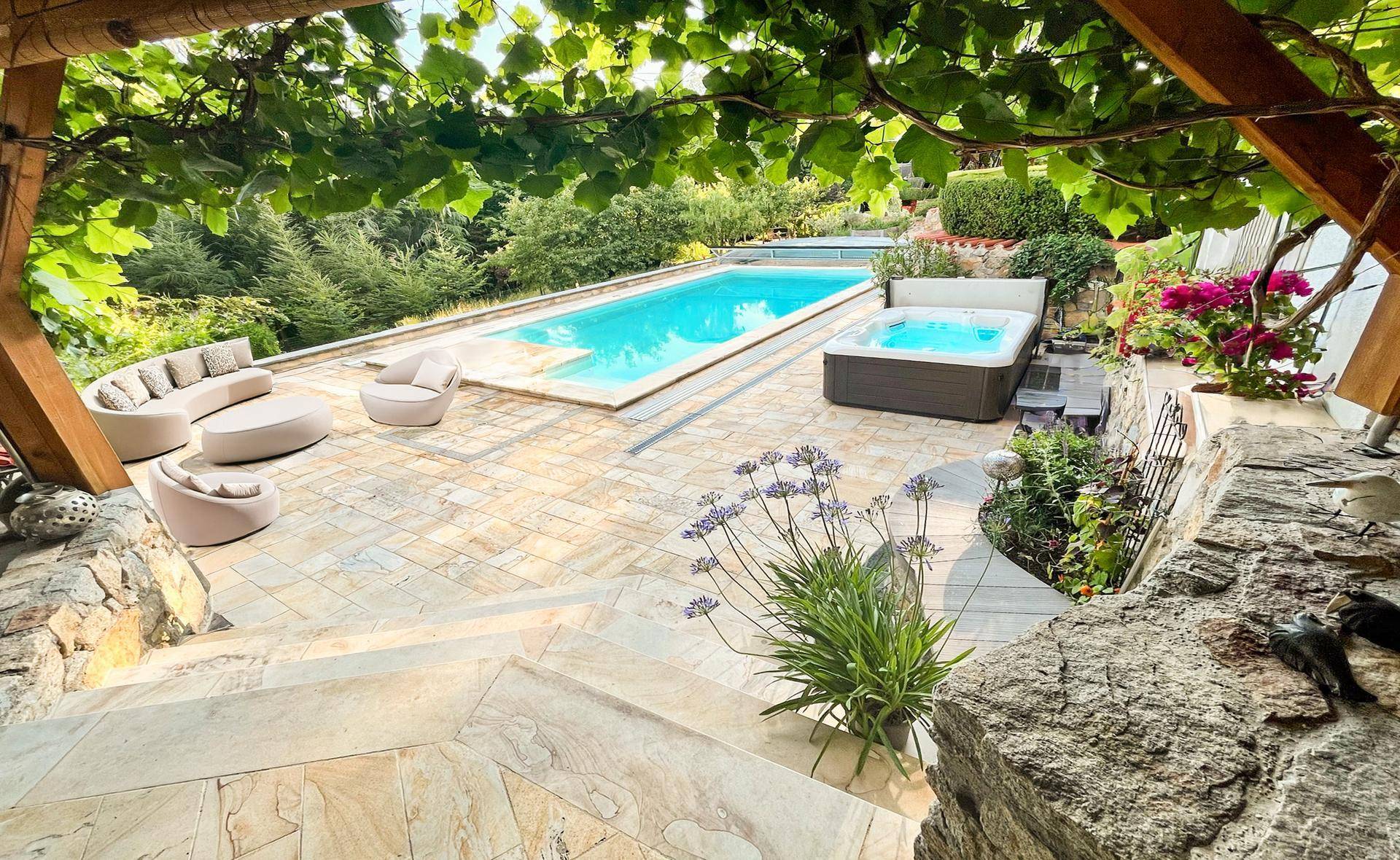 Großzügige Sonnenterrasse mit Pool, Whirlpool und bequemen Lounge-Möbeln.