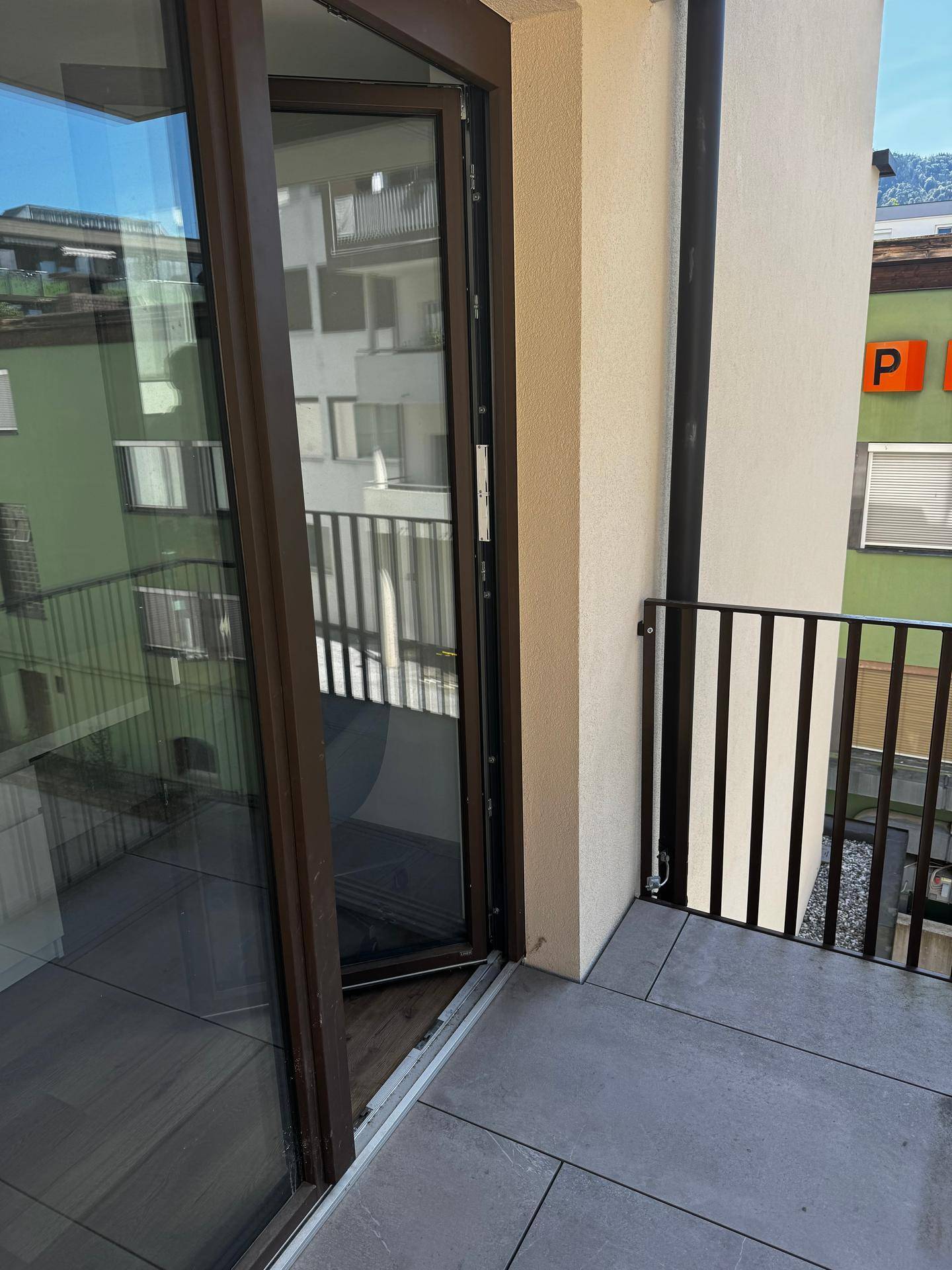 Balkon mit Fliesenboden und Metallgeländer, bietet einen Blick auf die umliegenden Gebäude.