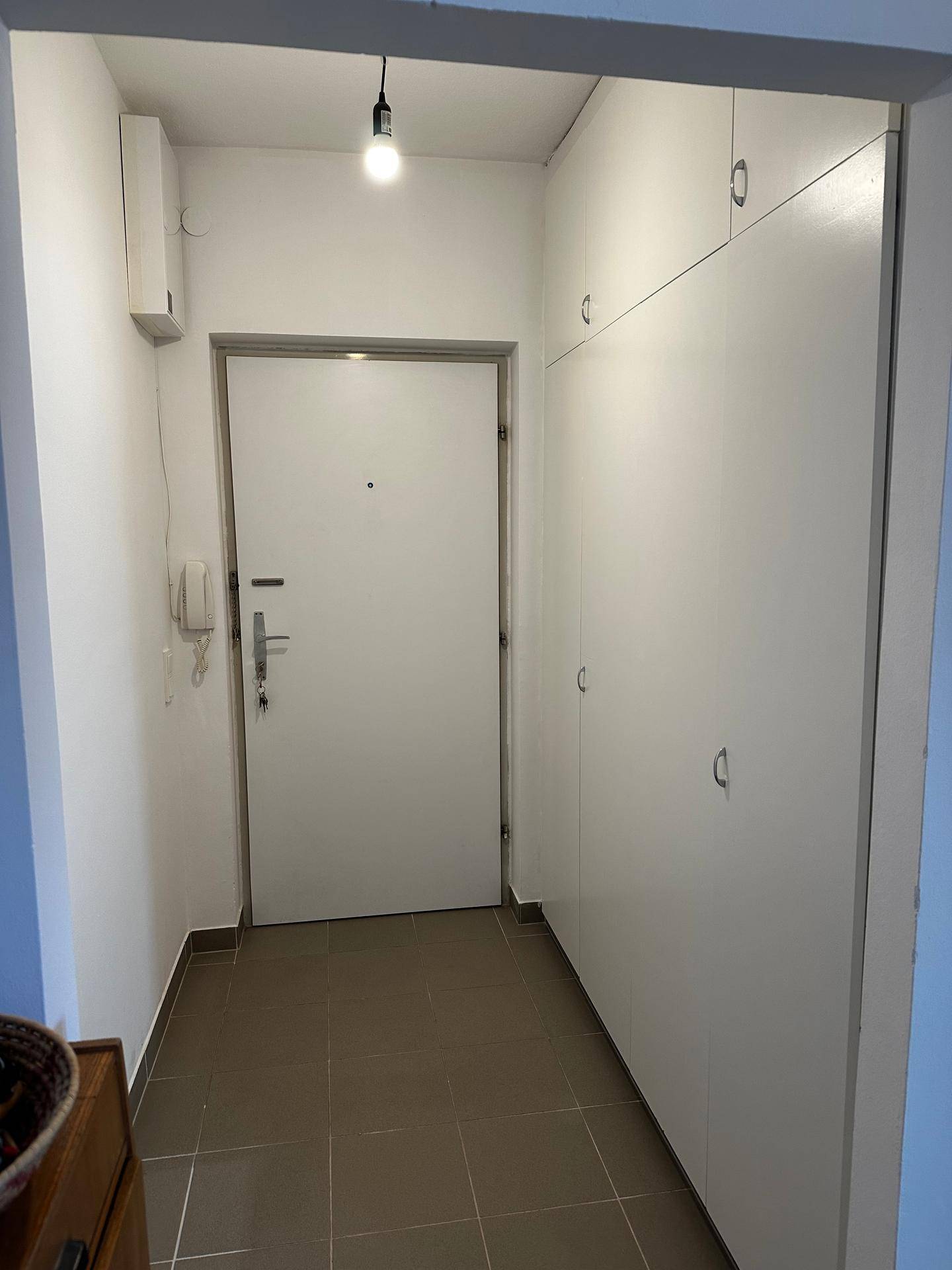 Heller Eingangsbereich mit Fliesenboden, Einbauschränken und der Wohnungseingangstür.