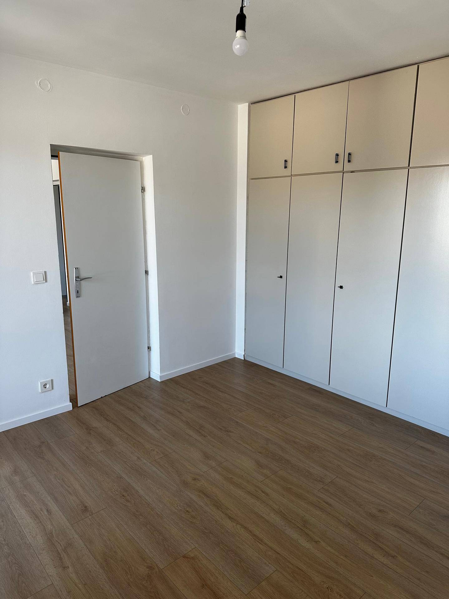 Helles Schlafzimmer mit integrierten Einbauschränken und modernem Laminatboden.