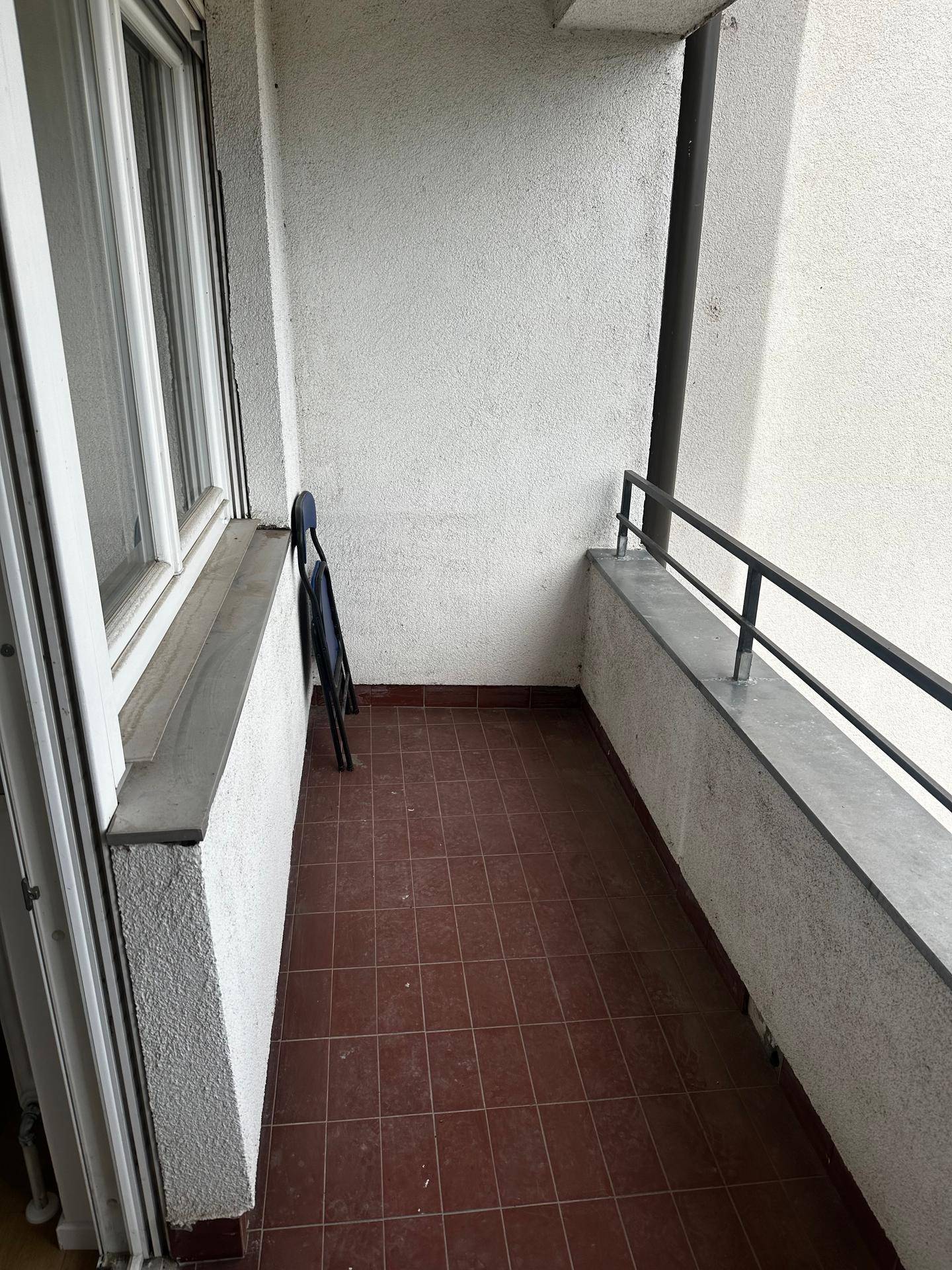 Schmaler Balkon mit Terrakotta-Fliesen und Metallgeländer, ideal für einen kleinen Sitzbereich.