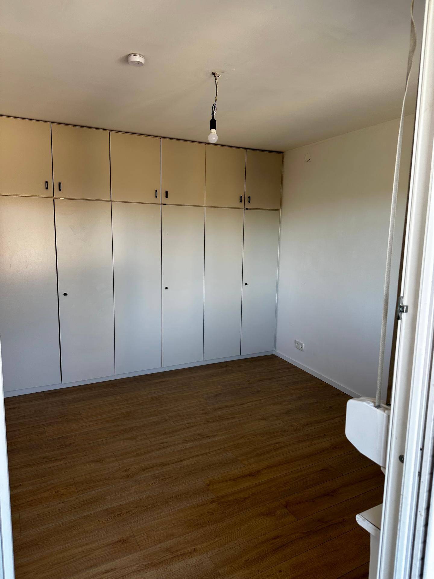 Schlafzimmer mit praktischen Einbauschränken entlang einer Wand und Laminatboden.