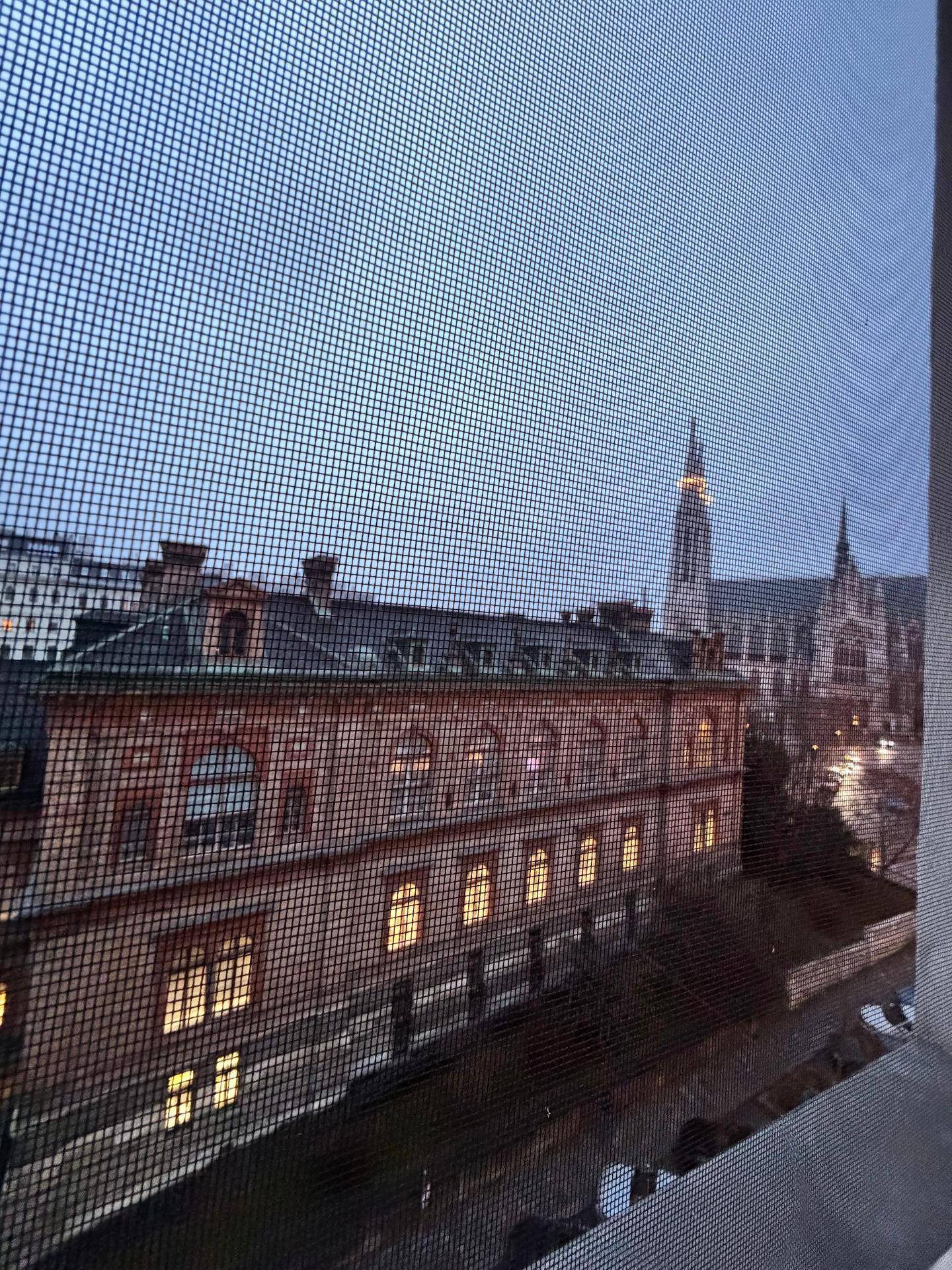 Abendlicher Blick aus dem Fenster auf ein historisches Gebäude und eine Kirche.