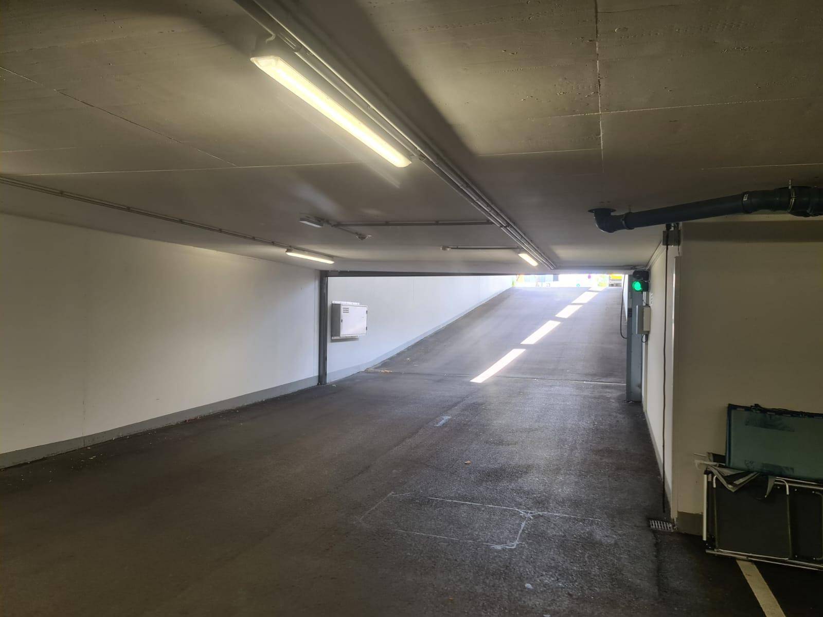 Helle Einfahrtsrampe zur Tiefgarage mit effizienter Beleuchtung und klaren Wänden.