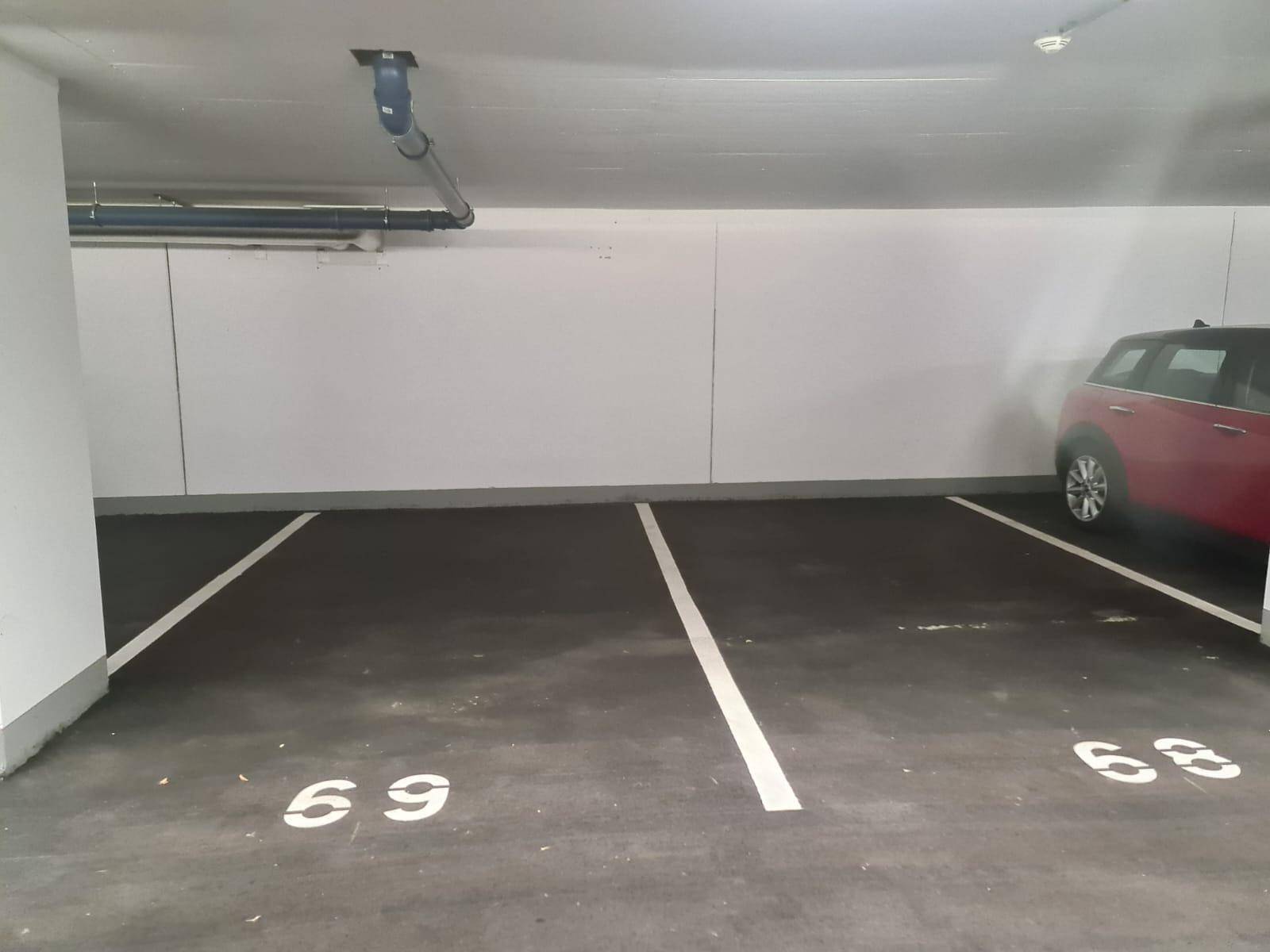 Markierte Parkplätze in der Tiefgarage mit sichtbaren Nummern und Deckeninstallationen.