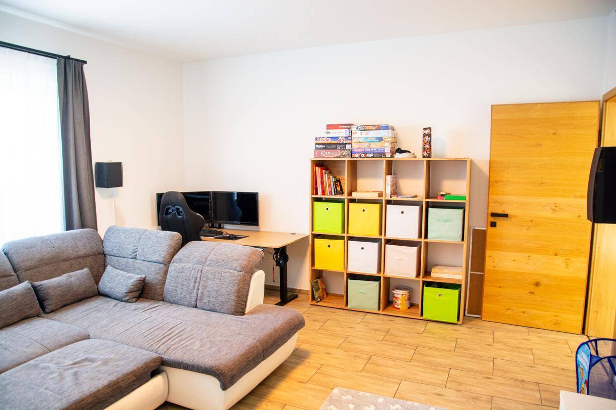 Wohnlicher Medienraum mit bequemer Couch, Regalen und einem Arbeitsbereich.