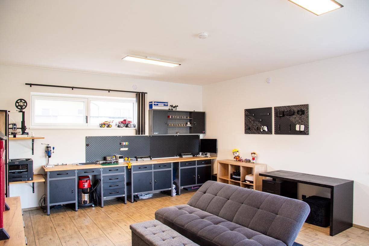 Funktionaler Hobbyraum mit Werkbänken, Stauraum und einem Sofa für Pausen.