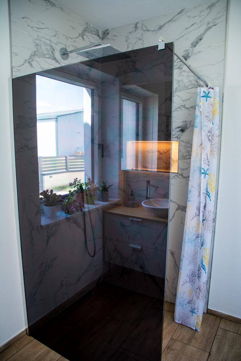 Modernes Badezimmer mit begehbarer Dusche, Glaswand und Fenster.