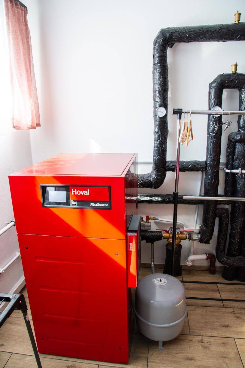 Rotes Heizsystem von Hoval mit isolierten Rohren in einem Technikraum.