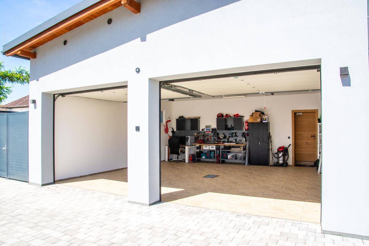 Moderne Doppelgarage mit zwei offenen Toren und gepflasterter Zufahrt.