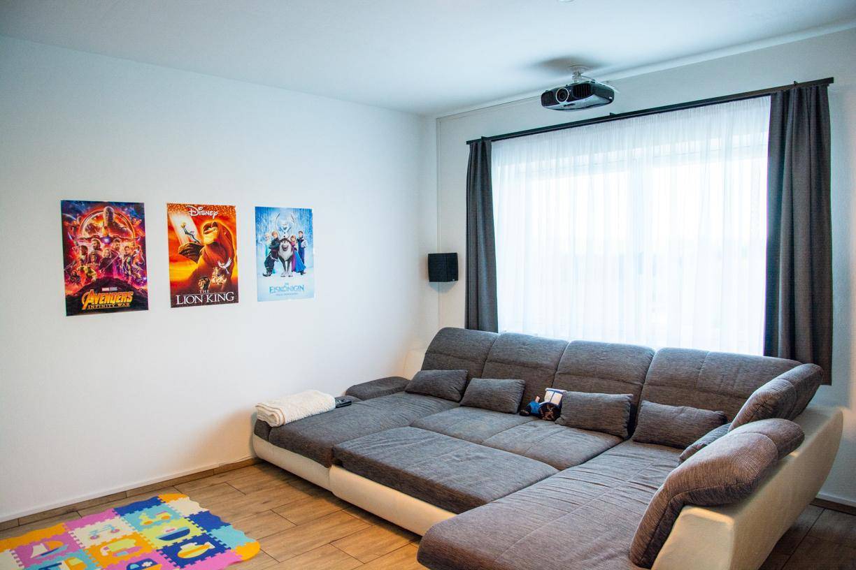 Gemütlicher Medienraum mit großem Ecksofa und Deckenprojektor für Filmabende.