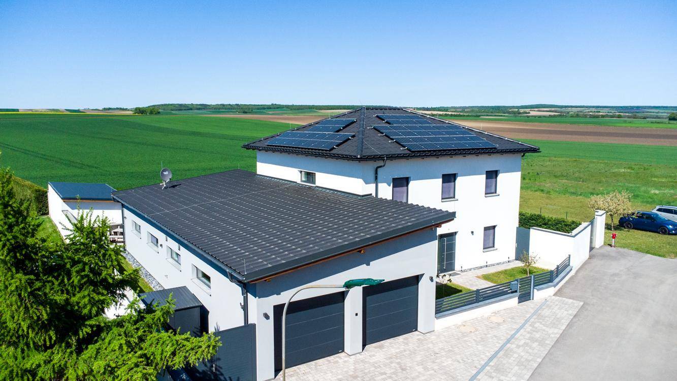 Luftaufnahme des Hauses und der Garage mit Solaranlagen auf den Dächern, umgeben von Feldern.