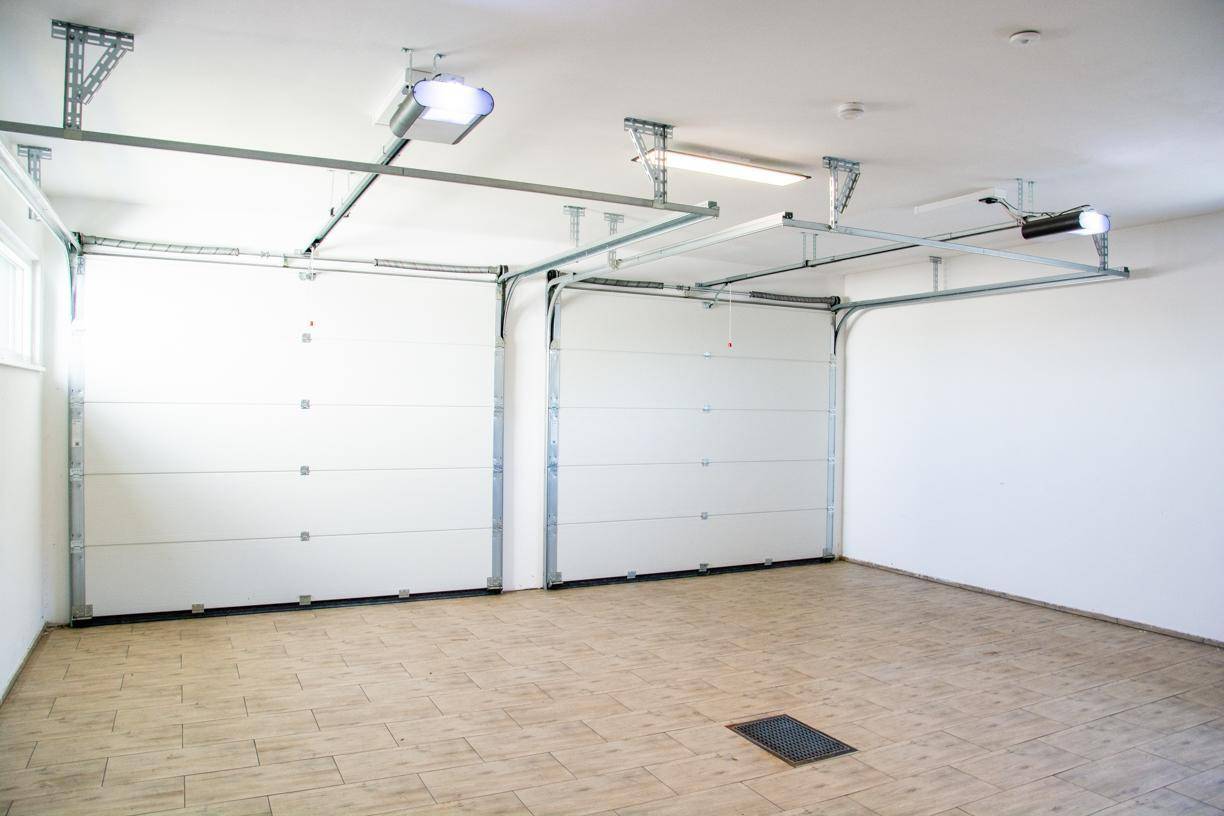 Saubere Doppelgarage mit geschlossenen Sektionaltoren und Fliesenboden.