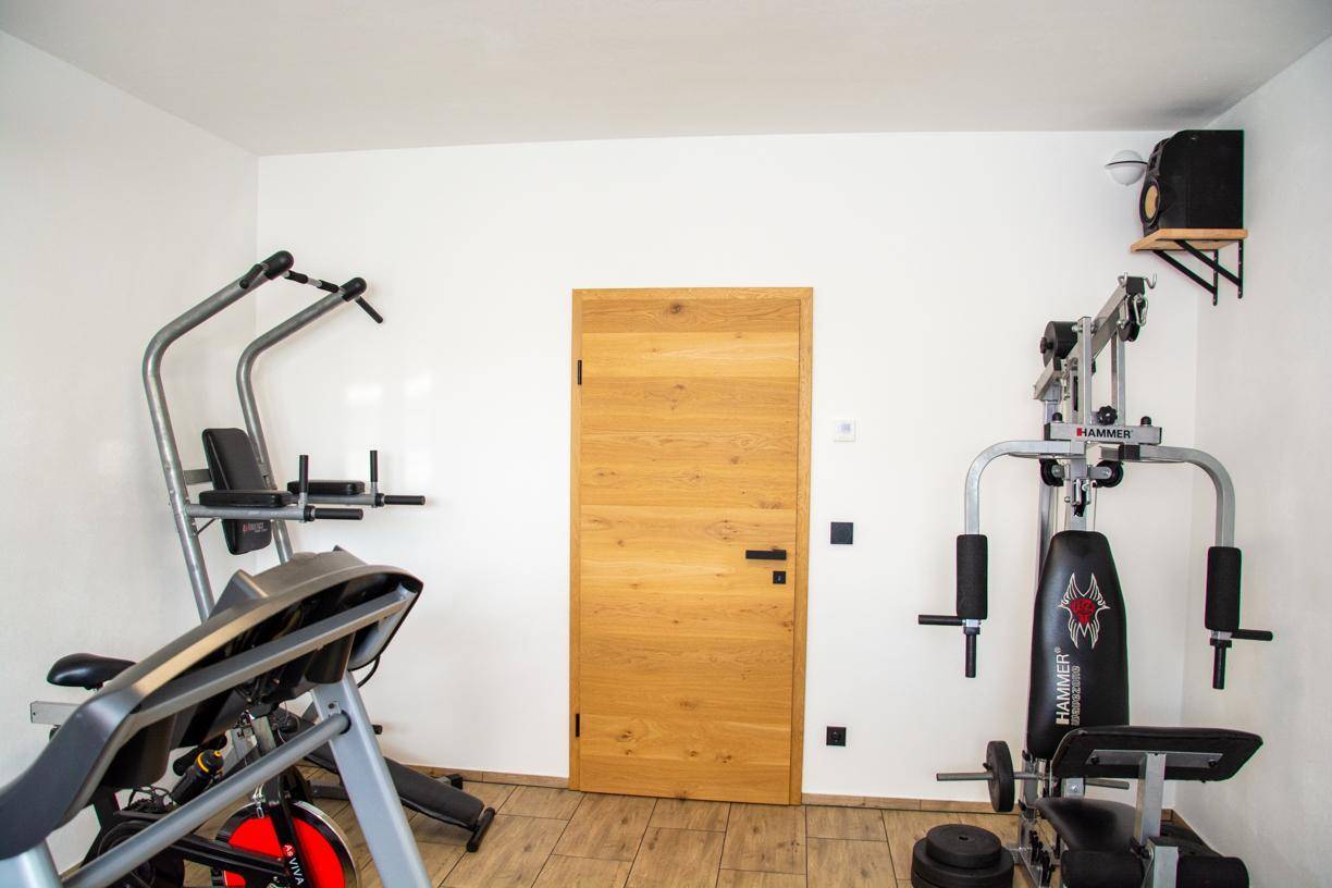 Fitnessraum mit Holztür und verschiedenen Trainingsgeräten für das Heimtraining.