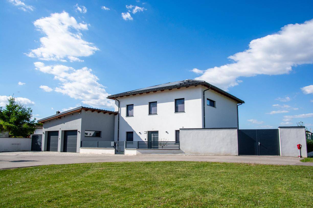 Vorderansicht des modernen Hauses und der Garage mit gepflasterter Auffahrt und Rasenfläche.