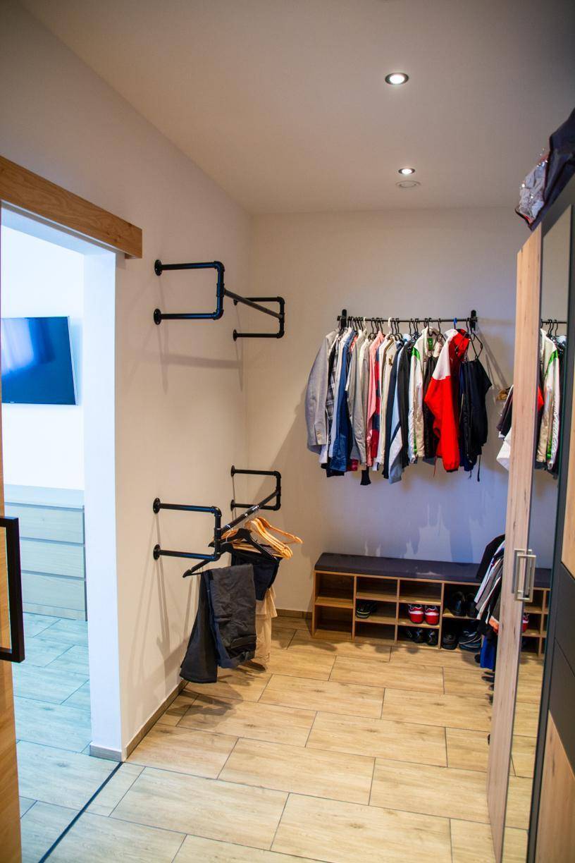 Geräumiger begehbarer Kleiderschrank mit offenen Kleiderstangen und Schuhregalen.