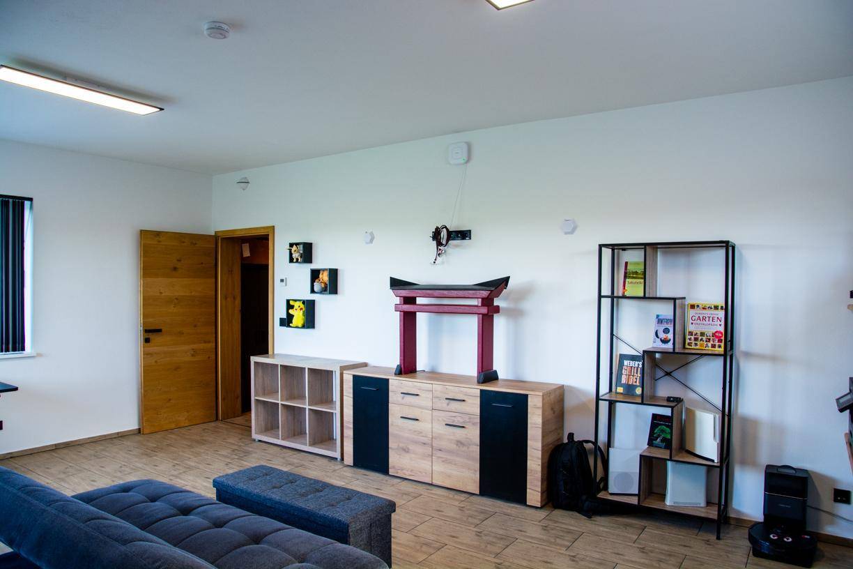 Geräumiger Wohnbereich mit Holzmöbeln, Regalen und einem bequemen Sofa.