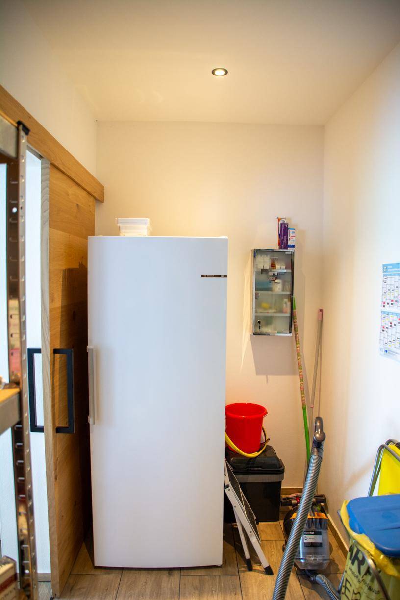 Praktischer Hauswirtschaftsraum mit Gefrierschrank und Stauraum für Reinigungsgeräte.