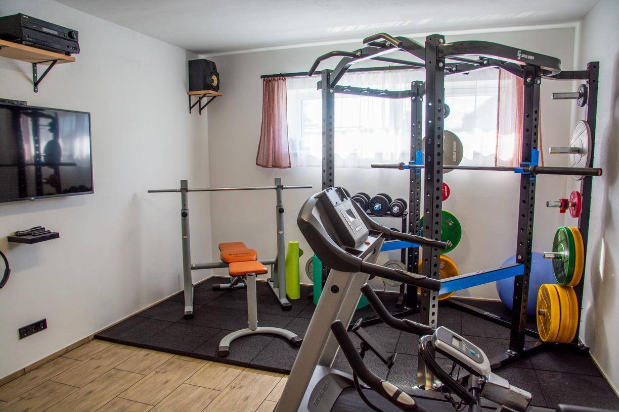 Gut ausgestatteter Fitnessraum mit Laufband, Hanteln und Kraftstation.