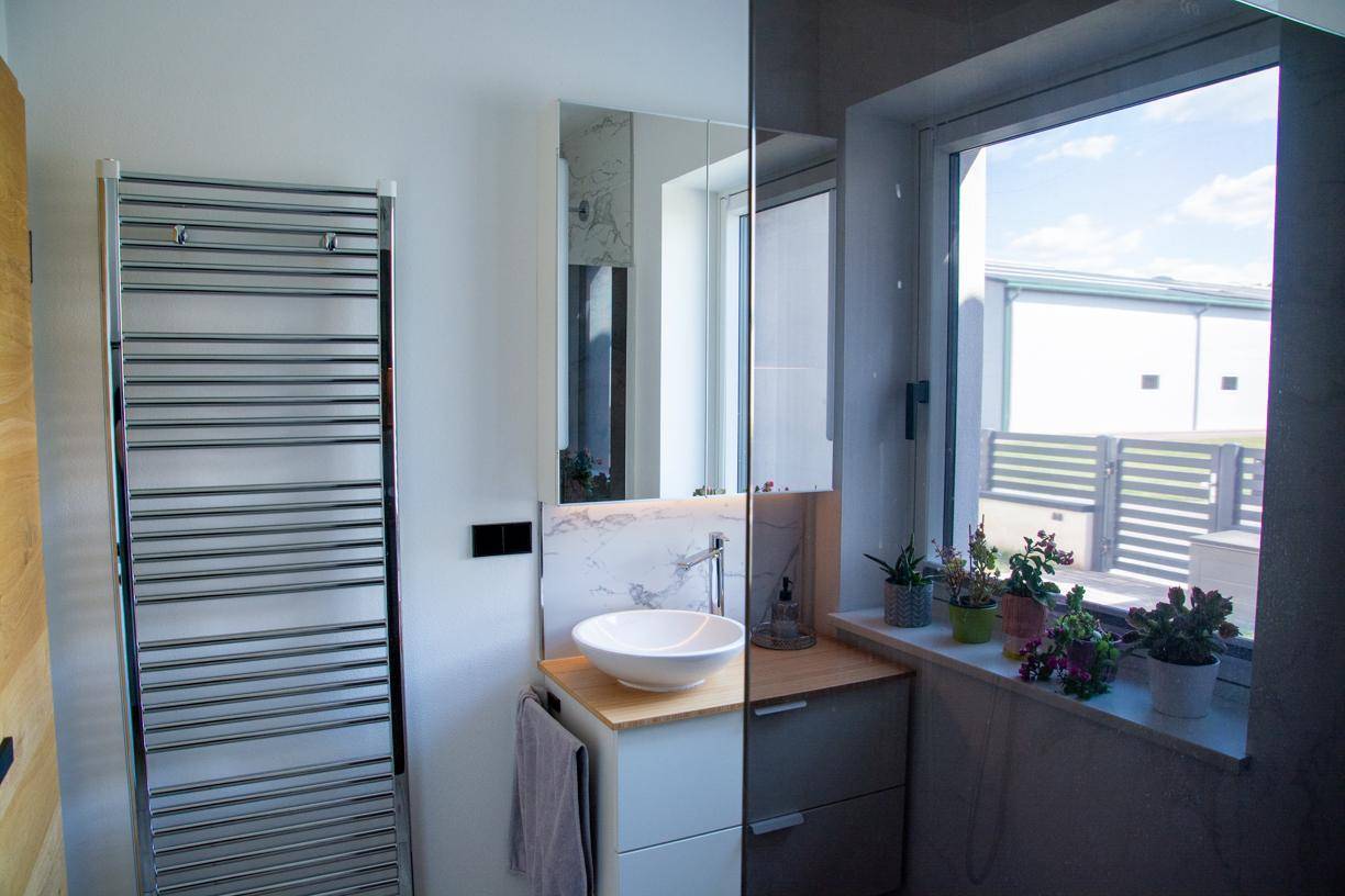 Helles Badezimmer mit modernem Waschbecken, Fenster und beheiztem Handtuchhalter.
