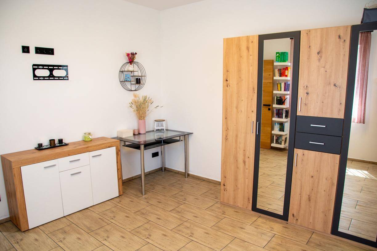 Schlafzimmer mit moderner Kommode, Spiegelschrank und dekorativen Elementen.
