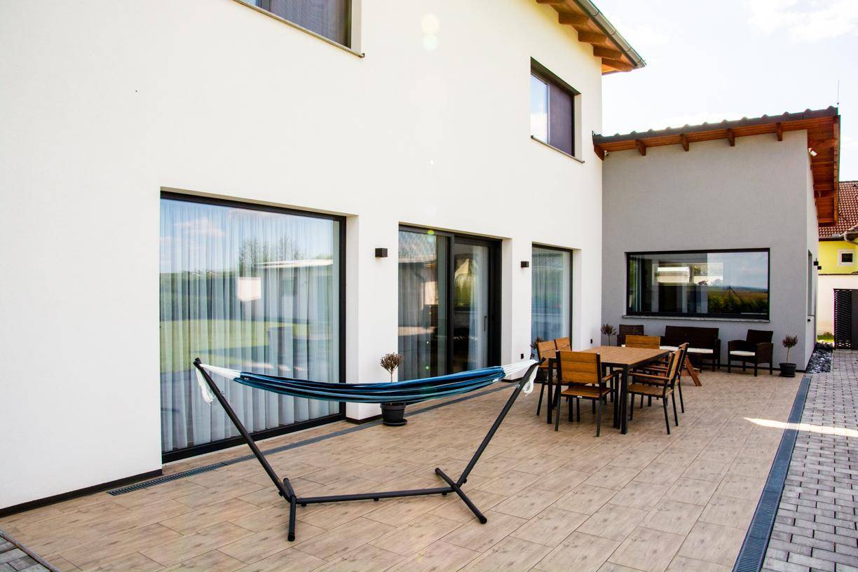Geräumige Terrasse mit Outdoor-Sitzbereich, Hängematte und großen Glasschiebetüren zum Haus.