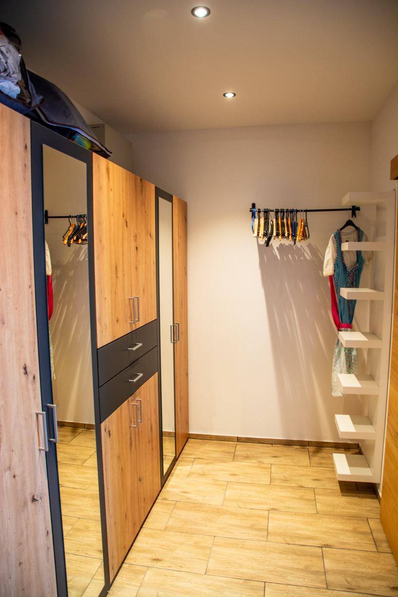 Begehbarer Kleiderschrank mit Spiegelschränken, Regalen und Kleiderstangen.