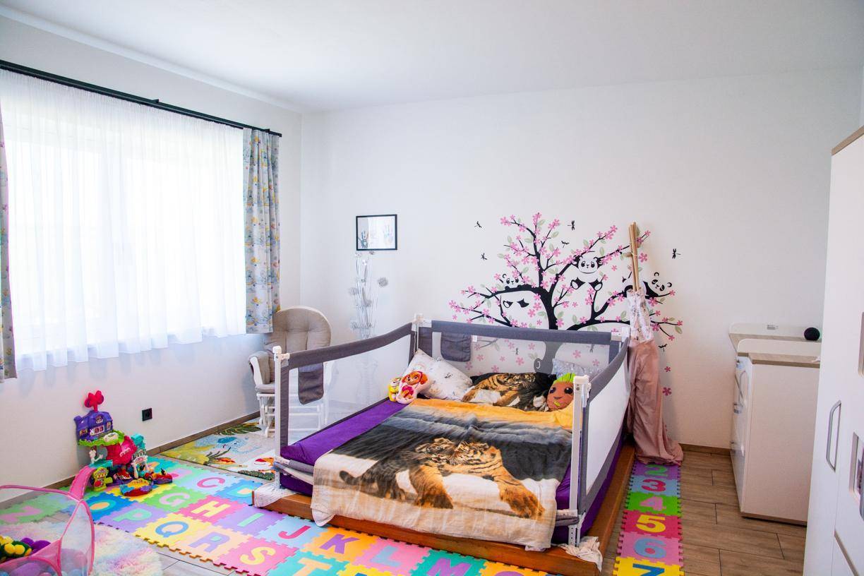 Kinderzimmer mit Babybett, bunter Spielmatte und Fenster für natürliches Licht.
