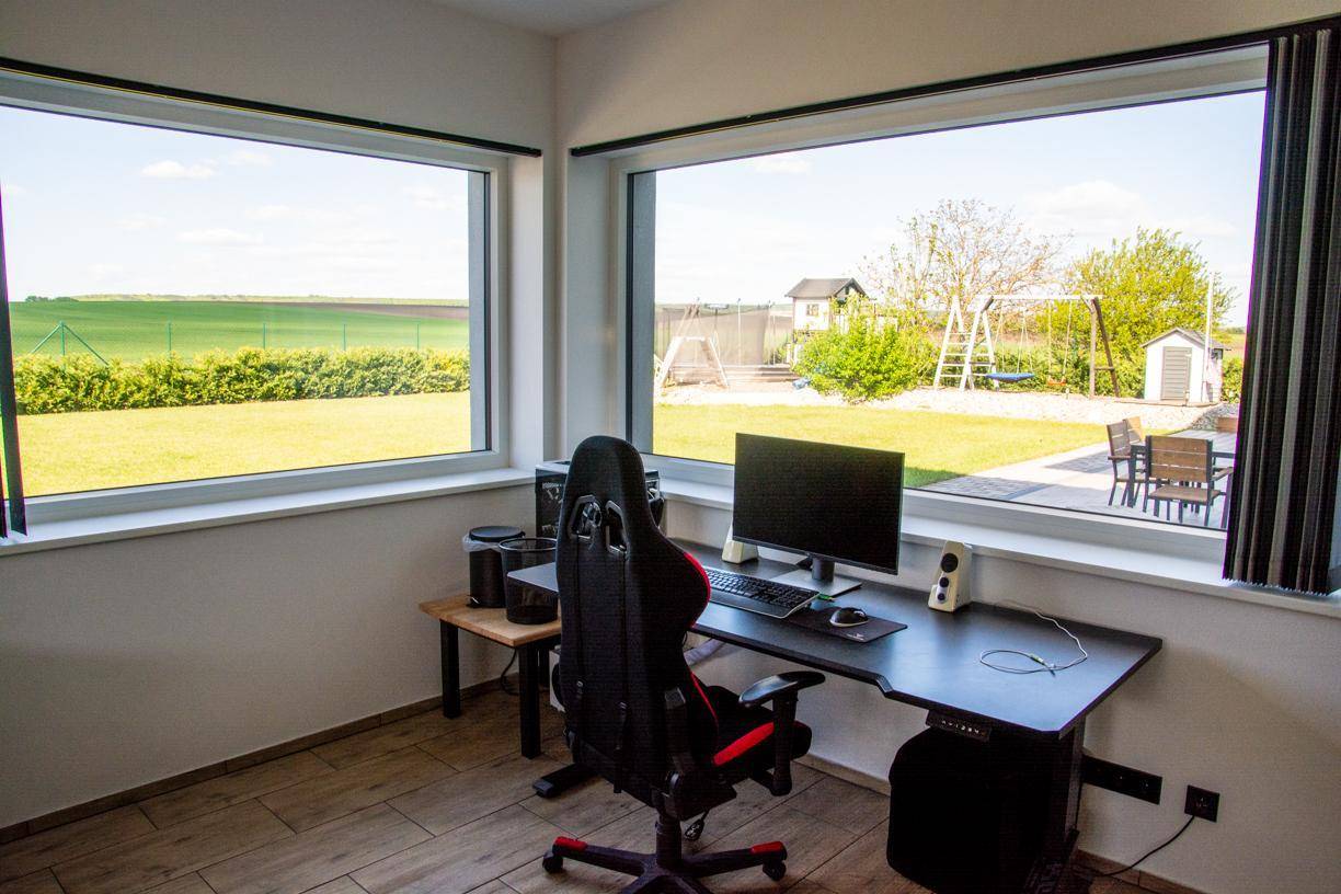 Helles Arbeitszimmer mit großzügigen Fenstern und Blick auf den Garten und Spielplatz.