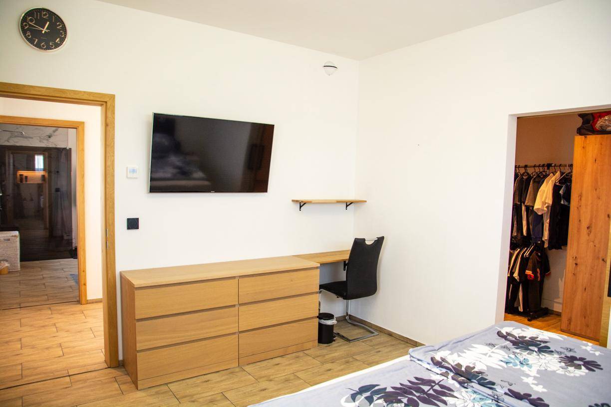 Schlafzimmer mit Doppelbett, Kommode und Zugang zu einem begehbaren Kleiderschrank.