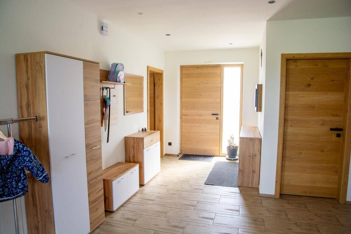 Heller Eingangsbereich mit modernen Holzmöbeln, Garderobe und Fliesenboden.